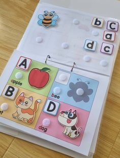 an open book with magnets and buttons on the pages, showing letters and animals