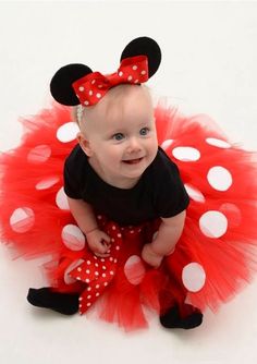 a baby girl wearing a minnie mouse outfit with red and white polka dots on it