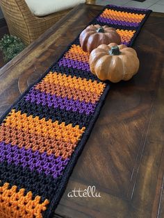 two pumpkins sitting on top of a table next to a crocheted runner