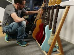 a man kneeling down next to guitars in a room