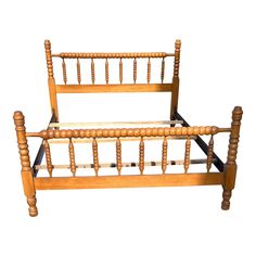 an antique wooden bed frame with turned legs and spindles on the headboard, isolated against a white background