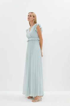 a woman in a long blue dress is looking off to the side with her hand on her hip