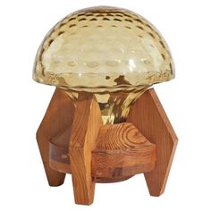 a glass and wood stool with an unusual design on the top, sitting in front of a white background