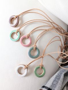 "Sweet little ceramic open circle necklaces to brighten your day with a little pop of color :)  These one of a kind, earthy-minimalist, o-ring shaped necklaces are made with reclaimed/recycled, stoneware speckled clay and make for a lovely and original gift to give to yourself or a special friend. Use as a necklace or passive essential oil diffuser in your car/home/office! This elegant and minimalist style ceramic pendant, hangs on an adjustable slide-knot leather cord and features an unglazed s Ceramic Necklaces, Ceramic Pendants, Pottery Jewelry, Ceramics Necklace, Necklace Ceramic, Ceramic Necklace Handmade, Porcelain Necklace Ceramics, Open Circle Necklace, Handmade Ceramic Jewelry