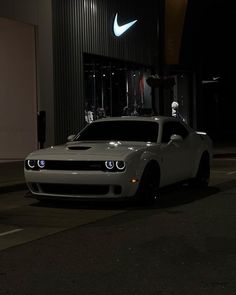 a white sports car parked in front of a building at night with the lights on