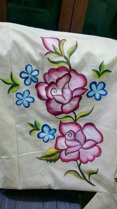 a white bag with pink and blue flowers painted on it's side sitting on a chair