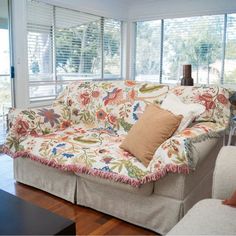 a living room filled with furniture and lots of window coverings on the windowsill