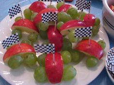 grapes and apples with checkered flags are arranged on a plate next to a bowl of cereal