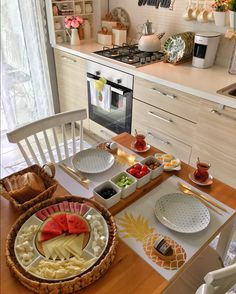 a wooden table topped with plates and bowls filled with food next to a stove top oven