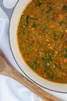 a white bowl filled with soup next to a wooden spoon on top of a table