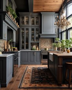 a kitchen with wooden floors and gray cabinets, an island countertop and potted plants on the windows sill