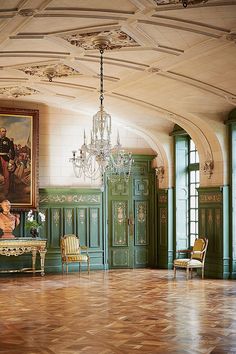 an ornate room with green painted walls and wooden floors, chandelier hanging from the ceiling