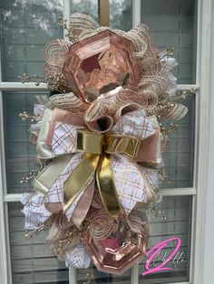 a pink and gold bow hanging from the side of a door with a window in the background