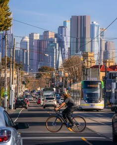 a man riding a bike down the middle of a street in front of tall buildings