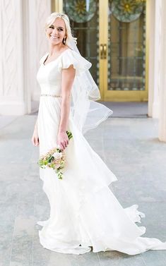 a woman in a wedding dress standing outside