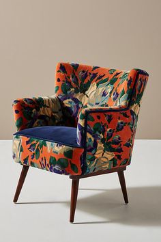 an orange and blue chair with floral print on it's back, sitting on a white floor