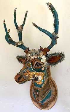 a deer head is decorated with blue and gold paint