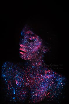 a woman's body covered in blue and pink glitter, with her eyes closed