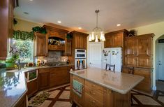 a large kitchen with wooden cabinets and marble counter tops, along with an island in the middle