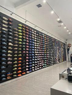 there is a large display of shoes on the wall in this store with people looking at them