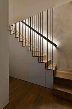 a wooden staircase with metal handrails next to a white wall and wood flooring