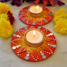 two red plates with candles on them sitting next to yellow flowers and pom - poms