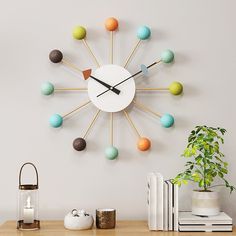 a clock that is on the wall next to a potted plant and some books