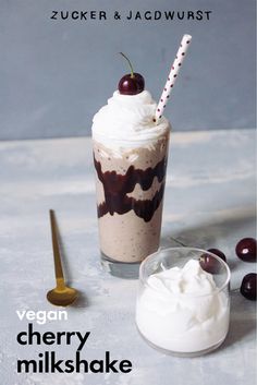 a dessert with whipped cream, cherries and chocolate sauce in a glass next to a spoon