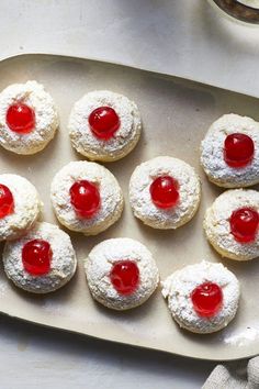 a pan filled with pastries covered in powdered sugar and topped with cherry jam