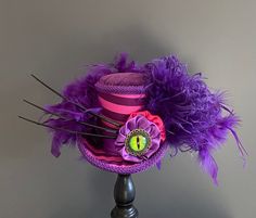 a purple and pink hat with feathers on it sitting on top of a wooden table