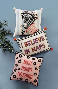 three pillows with different designs on them and one saying i believe in naps, the other says busy doing nothing