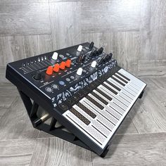 an electronic keyboard sitting on top of a wooden floor next to a gray tile wall