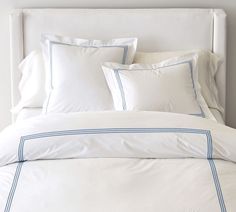 a bed with white sheets and blue trimmings