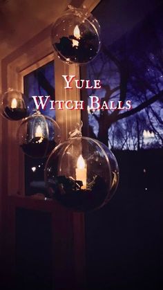 three glass balls hanging from a window sill with the words yule witch balls on them