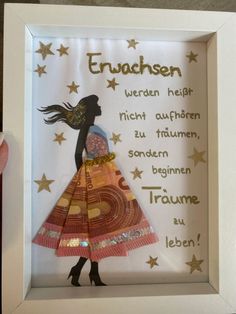 a paper cut out of a woman's dress in a white frame with gold stars