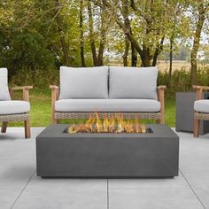 a fire pit sitting on top of a cement floor next to two couches and chairs