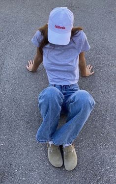 a person sitting on the ground with their hands in the air and wearing a hat