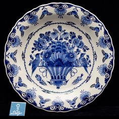 an ornate blue and white plate with flowers on the rim, in front of a black background