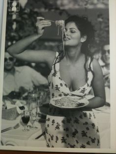 a black and white photo of a woman eating spaghetti