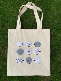 a tote bag with sheep on it sitting in the grass