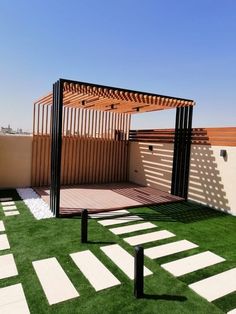 an outdoor area with grass and white tiles on the ground, covered in wooden slats