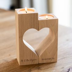 a wooden block with two candles in the shape of a heart