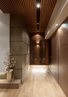 an empty hallway with wooden floors and lighting on the ceiling is lit by recessed lights