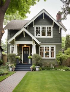 a gray house with white trim on the front door and two story windows, along with potted plants