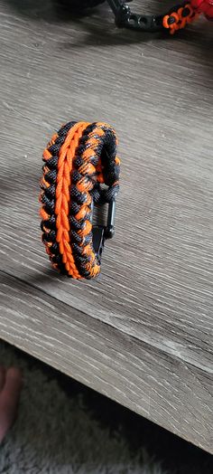 an orange and black bracelet sitting on top of a wooden table