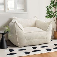 a white bean bag chair sitting on top of a wooden floor next to a potted plant