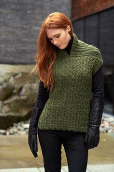 a woman walking down the street wearing black gloves and a green knitted sweater with an open neck