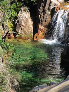 there is a small waterfall in the middle of this lake with green water and rocks