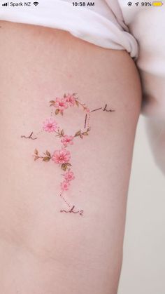 a woman's lower thigh with pink flowers on it and the word love written in cursive writing