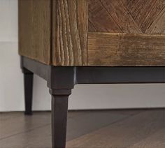 a close up view of the bottom of a wooden dresser with metal legs and wood paneling